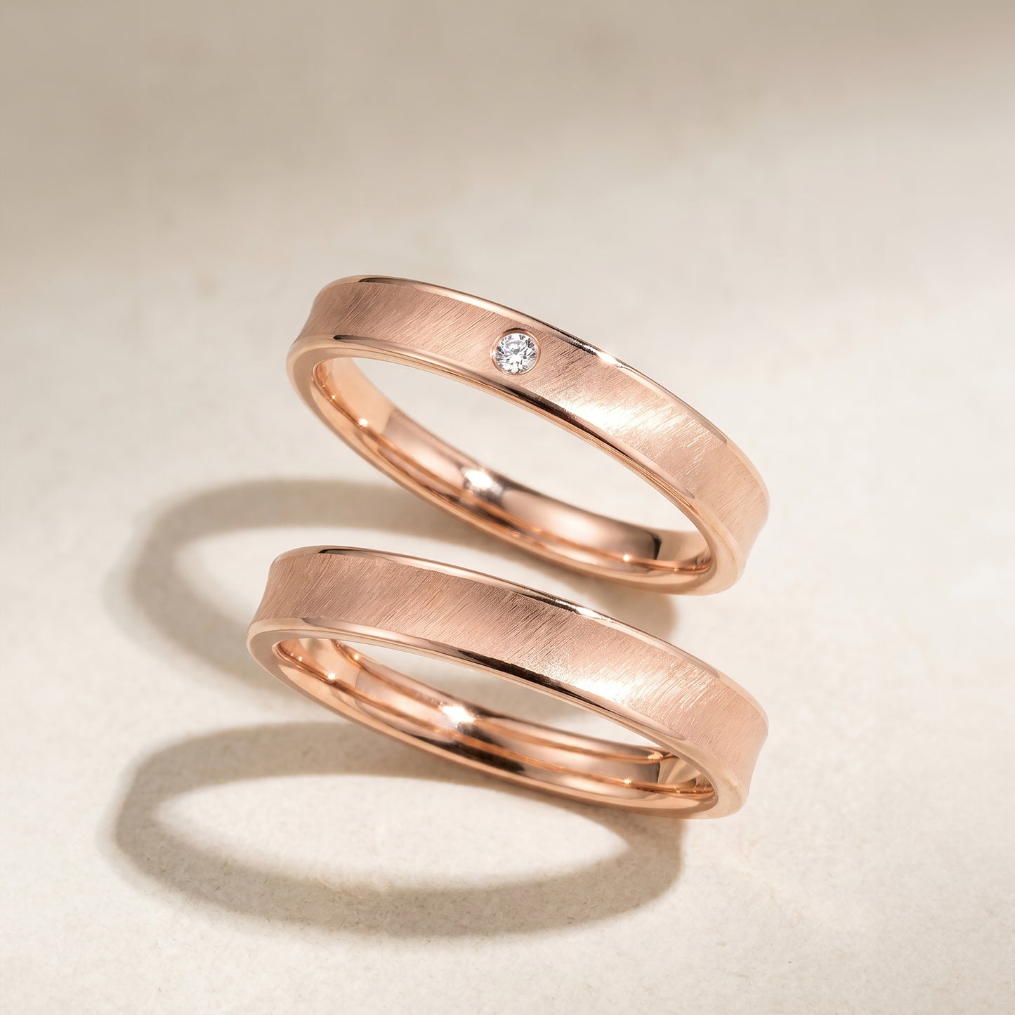 A set of rose gold wedding band on a beige background. Lady's band with diamond