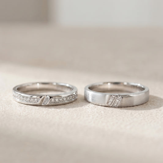 A pair of white gold wedding band with diamond accents on a light beige surface