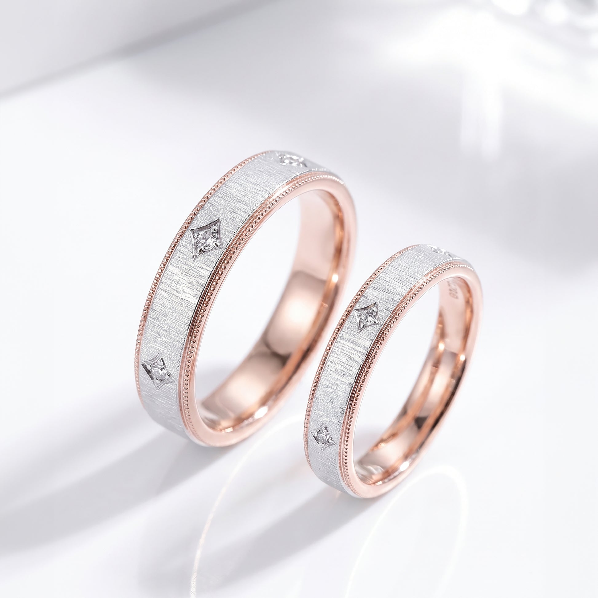 Two rose gold and white gold wedding bands with diamond accents, displayed on a clean white reflective surface.